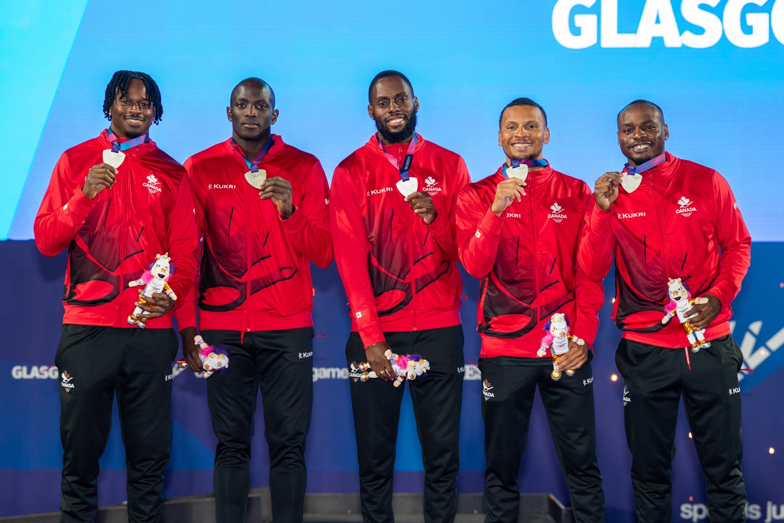 Team Canada men's 4x100m relay on the Glasgow 2026 podium with silver medals: Aaron Brown, Jerome Blake, Brendon Rodney, Andre De Grasse, Duan Asemota.
