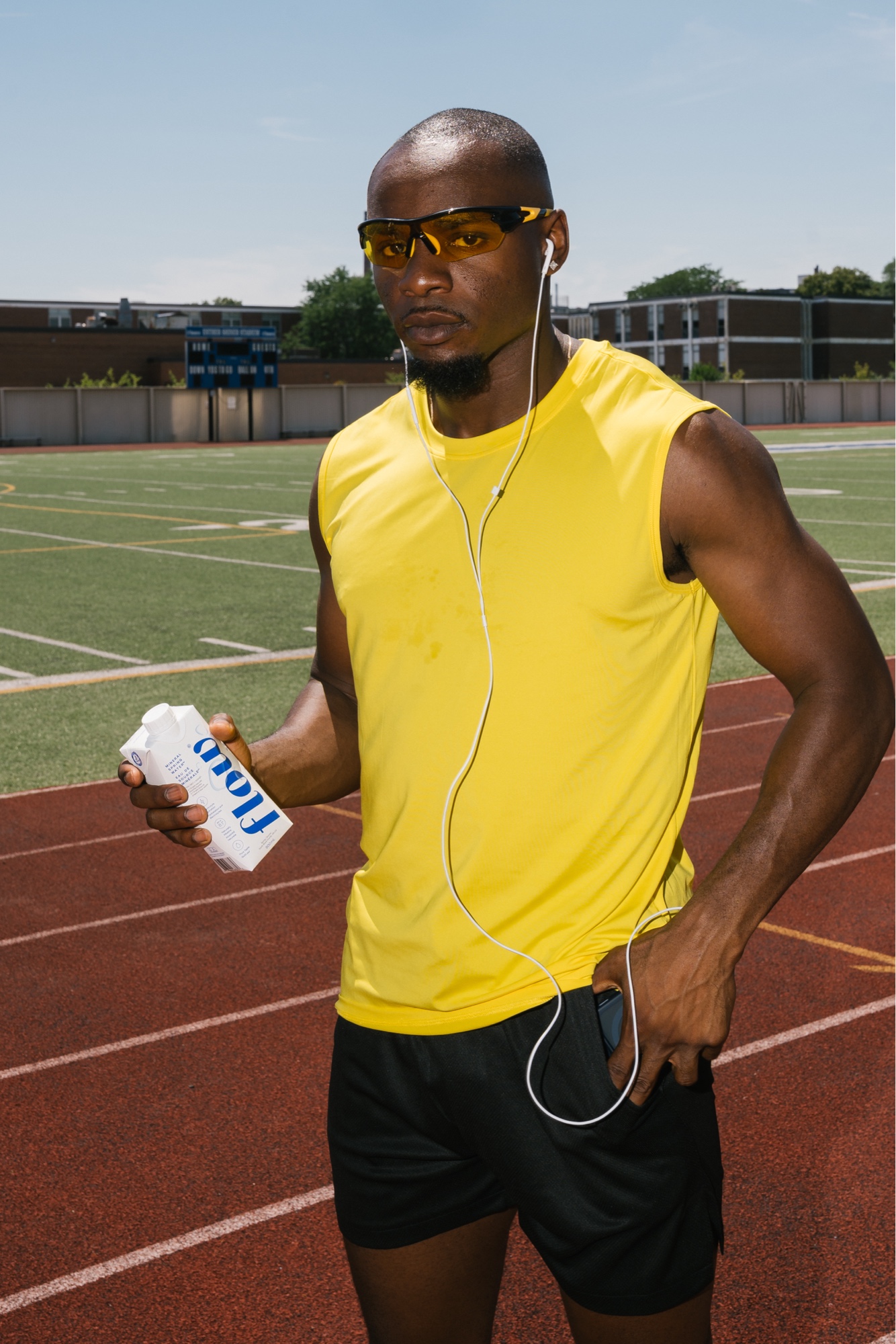 Yellow kit portrait with white earbuds and Flow Water