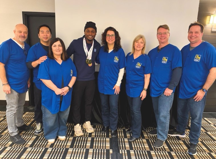 Duan Asemota with medals around his neck standing with the RBC branch team in blue RBC jerseys